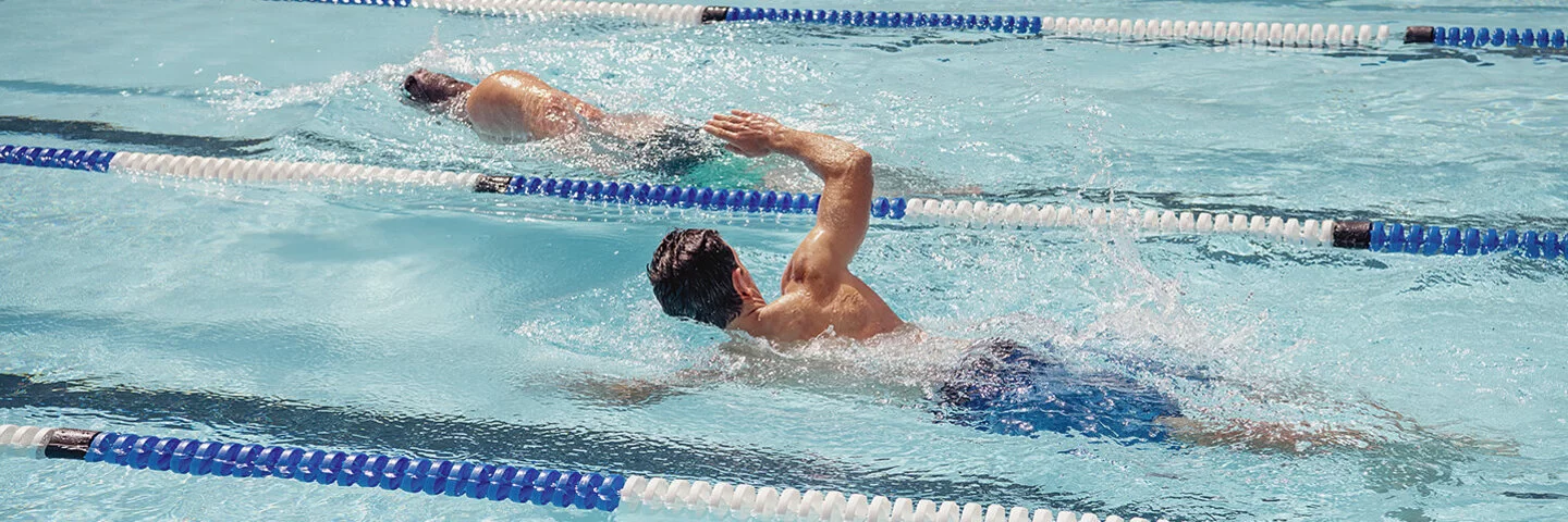 Zwei Männer ziehen im Schwimmbad Bahnen.